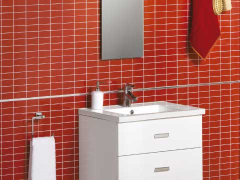 Aseos de cortesía donde aparece un mueble blanco y pequeño en un cuarto de baño con baldosas rojas.